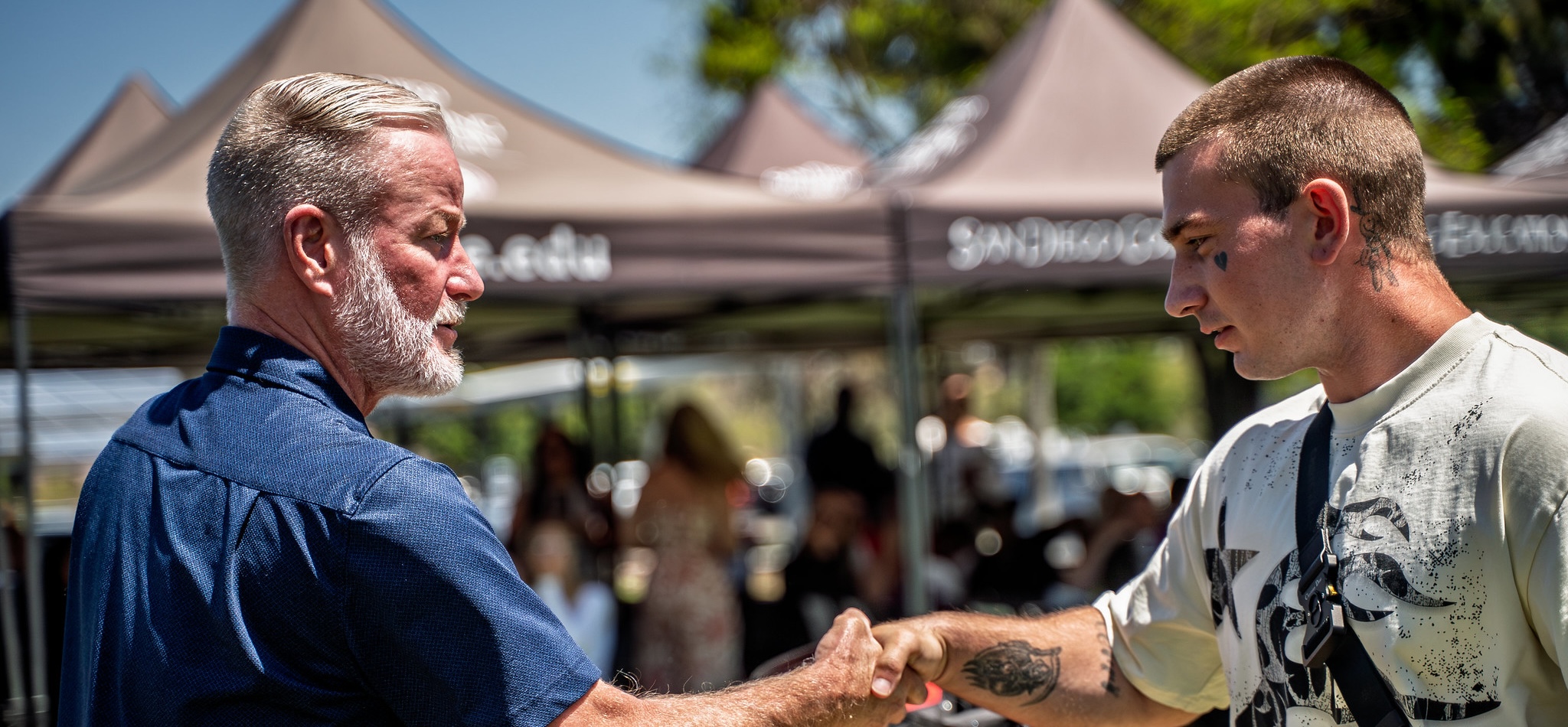 Four students standing close together, smiling outside. 