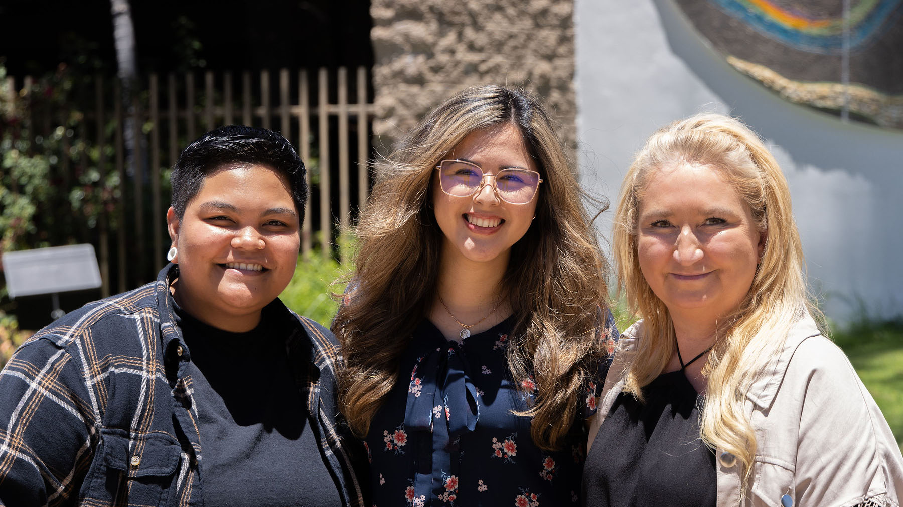 Three students smiling for picture outside